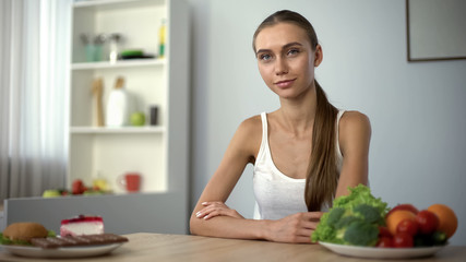 Obraz na płótnie Canvas Fit woman choosing vegetables instead of junk food, healthy diet, lifestyle