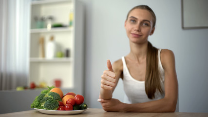 Skinny girl showing thumbs up, recommending vegetables, health, proper nutrition