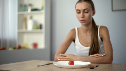Underweight woman looking at small portion of meal, exhausted body, severe diets - obrazy, fototapety, plakaty