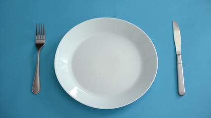 Empty plate and fork with knife set on table, dishwashing detergent, background