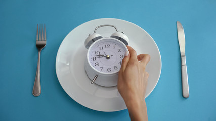 Daily regime, alarm clock on plate, adhere to diet time, proper nutrition