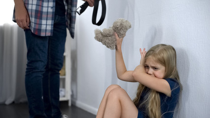 Violence in family, crazy father threatening frightened little girl with belt