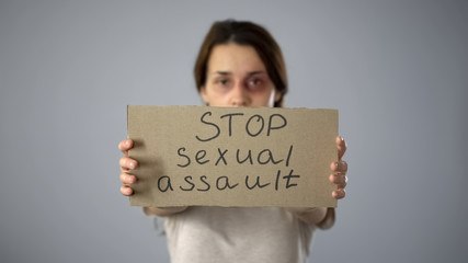 Stop sexual assault sign in bruised woman hands, fight against harassment