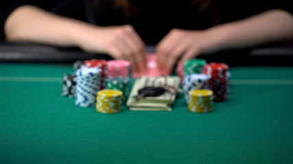 Woman checking her cards with all chips, money and house keys on table, gambling