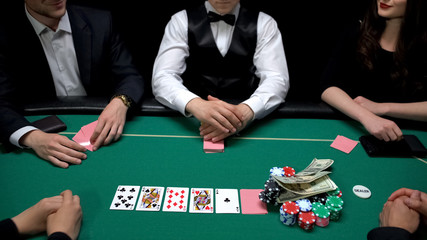 Player raising stakes putting dollars on chips at casino poker game, gambling