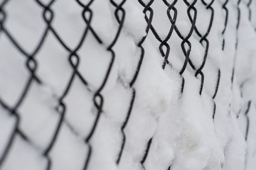 Metal wire mesh fence covered with snow during the winter.