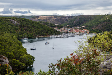 Fototapeta na wymiar mountain valley with a very wide river, a village in the distance and a small harbor with many yachts and boats, the shores are overgrown with forests