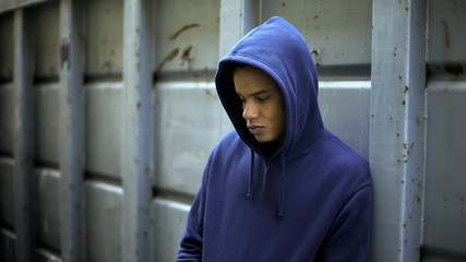 Sad afro-american boy lonely staying in gateway, bullying, race discrimination