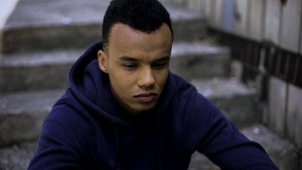 Hopeless afro-american teen sitting on steps in ghetto, concerned about future