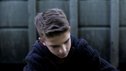 Depressed teenager boy feeling hopelessness, regretting wrong doings, sorrow
