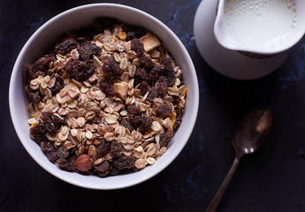 Bowl with muesli, milk jug and spoon viewed from above