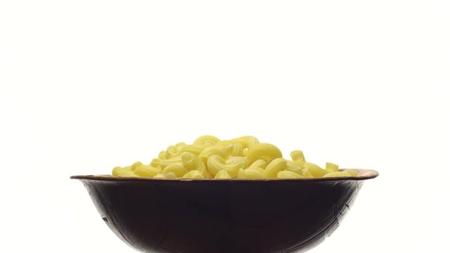 Raw macaroni in rotation. Elbow macaroni.  Macaroni rigati close up.  Raw pasta  isolated on white. Italian cuisine concept.