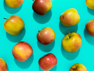 Apples with hard shadow on aqua background, flat lay image.