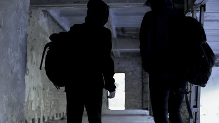 Criminals wearing black walking in abandoned house, crime planning, conspiracy