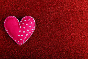 Obraz premium Red heart made of felt on a red background. Handmade blank for greeting card, copy space.
