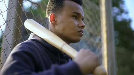 Teenage boy holding baseball bat, youth gang in ghetto, juvenile delinquency