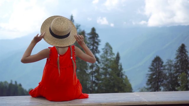 Beautiful happy little girl in mountains in the background of fog