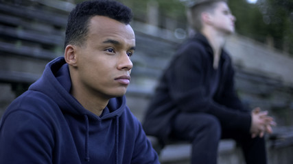 Upset teenagers sitting on stadium tribune, watching sports game of youth team