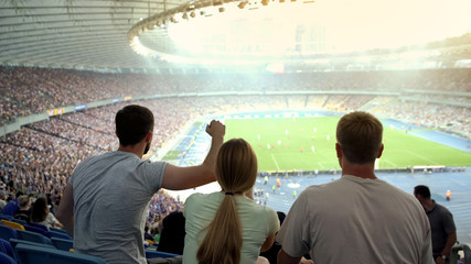 Football fans supporting favorite team at stadium, cheering for victory, match