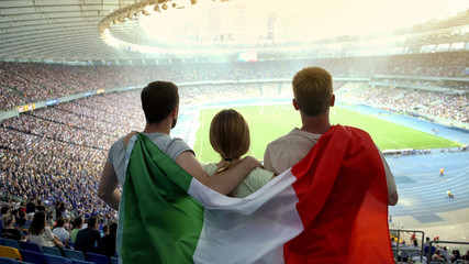 Football fans with Italian flag jumping at stadium, cheering for national team