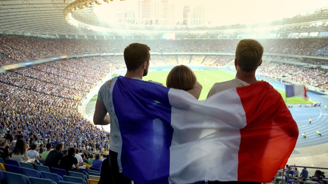 Football fans with French flag jumping at stadium, cheering for national team
