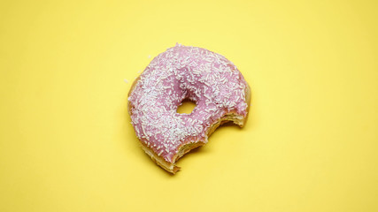 Delicious glazed bitten donut on yellow background, favorite children food