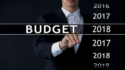 2018 budget, businessman selects file on virtual screen, annual financial report