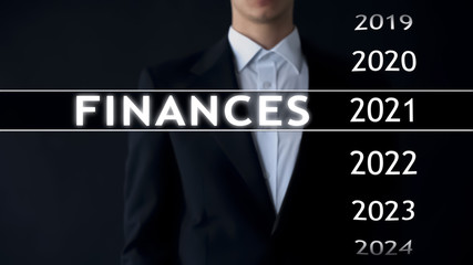 Businessman selects 2021 finances report on virtual screen, money statistics