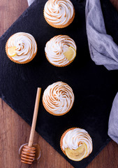Fototapeta na wymiar Lemon muffins with protein cream on a slate board with powdered sugar and honey