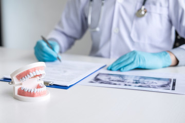 Male doctor or dentist working with patient tooth x-ray film, model and equipment used in the...