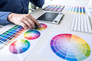 Male creative graphic designer working on color selection and color swatches, drawing on graphics...