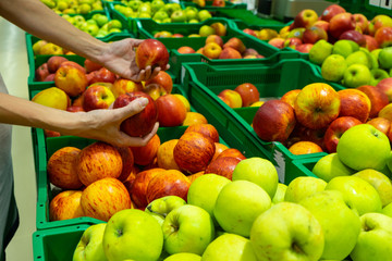 The girl chooses apples in the supermarket.