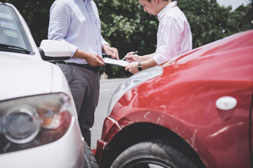 Insurance Agent examine Damaged Car and customer filing signature on Report Claim Form process after accident, Traffic Accident and insurance concept
