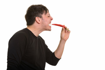 Profile view of crazy  Caucasian man eating red pepper