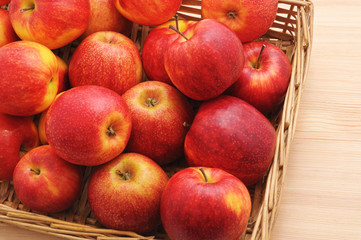 Red apples in wicker basket on table.