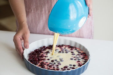 Young woman cooking in kitchen.Clafoutis cherry pie