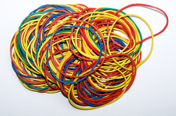 A pile of multi-colored rubber bands stationery, ready to use, is disordered mass on a white plane,...