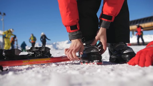 Skier stepping into the ski bindings with his ski boots on a sunny morning. Fixing the ski boot. Skiing close up.