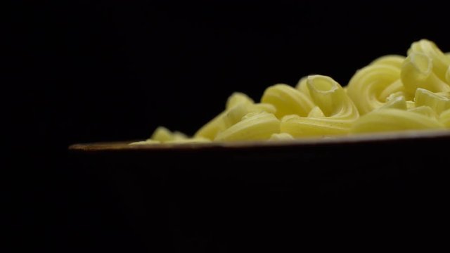 Raw macaroni in rotation. Elbow macaroni. Macaroni rigati close up.  Raw pasta  black background. Italian cuisine concept.