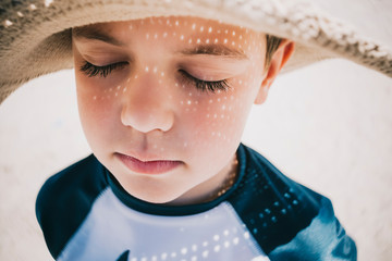 Close up of boy with eyes closed wearing hat on beach