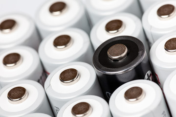 AA batteries are located close to each other. Close-up of all white batteries, except one black, on a white background. Battery technology