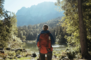 Rear view of woman with backpack standing by lake in forest