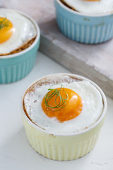 Baked eggs in ramekins close view, selective focus