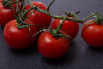 Organic red cherry tomatoes on the vine and and natural stone background.
