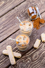  Iced coffee with ice and milk on a wooden table.