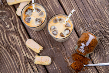 Iced coffee with ice and milk on a wooden table.