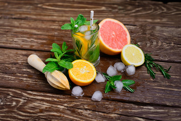  Lemonade with ice, grapefruit and rosemary on a wooden table. Cold drinks.