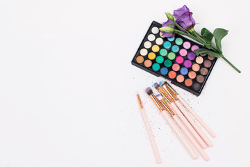 Cosmetics and makeup brushes on white background