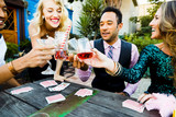 Smiling multiethnic friends toasting drinks at table during cocktail party in backyard