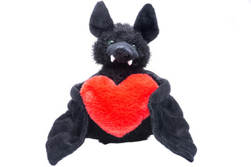 Stuffed funny black bat toy with red fluffy heart on white background